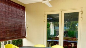 A covered patio area with a table and chairs, a ceiling fan, and a view through a glass door. - Seaside House-Flic en Flac (Flic en Flac)