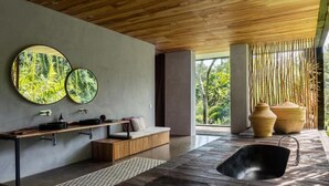 A modern bathroom with a wooden bench, a black sink, and two round mirrors on the wall. - Peaceful river and jungle views, 6 bedrooms, close to beaches. (Tabanan)