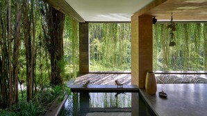 A room with a large window, a wooden bench, and a small table with a vase and a candle. - Peaceful river and jungle views, 6 bedrooms, close to beaches. (Tabanan)