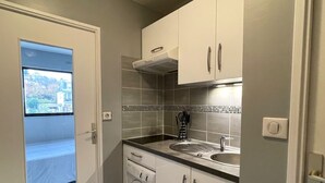 A compact kitchen with a built-in washer and dryer, a window with a view, and a tiled backsplash.