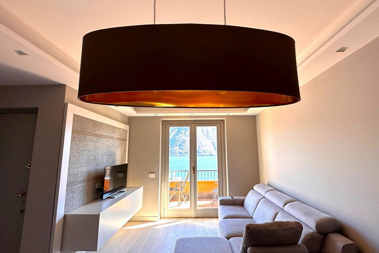 A modern living room with a large black pendant light, a sofa, and a television on a stand.