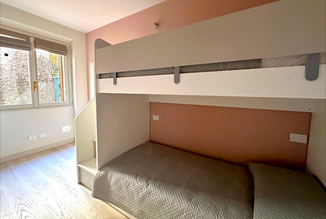 A bunk bed room with a window, a staircase, and a view of the outside.