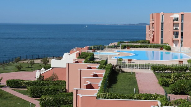 Um resort com piscina, vista para o mar e um edifício com varandas.