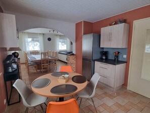 A compact kitchen with a dining area, a refrigerator, and a coffee maker.