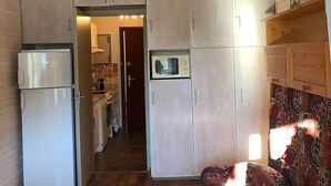 Een kleine keuken met een koelkast, magnetron en houten kastjes.