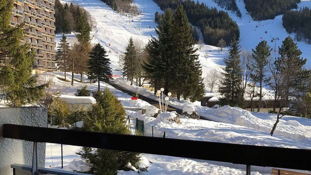 Een besneeuwd landschap met een piste, bomen en een gebouw met een opvallend ontwerp.