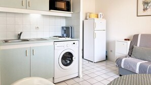 Une cuisine compacte équipée d’un lave-linge, d’un four à micro-ondes et d’un réfrigérateur.
