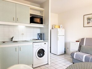 Eine kompakte Küche mit Waschmaschine, Mikrowelle und Kühlschrank.