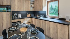 A modern kitchen with wooden cabinets, a black countertop, and a dining area set for four.