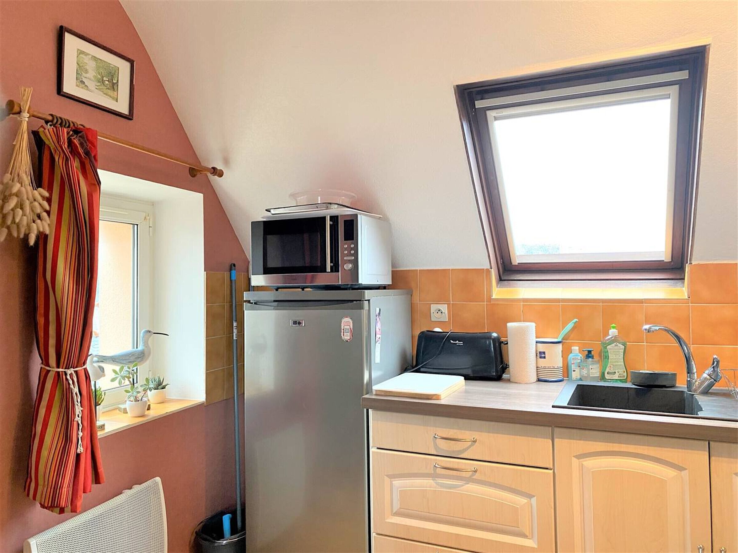 A compact kitchen with a microwave, refrigerator, and sink.