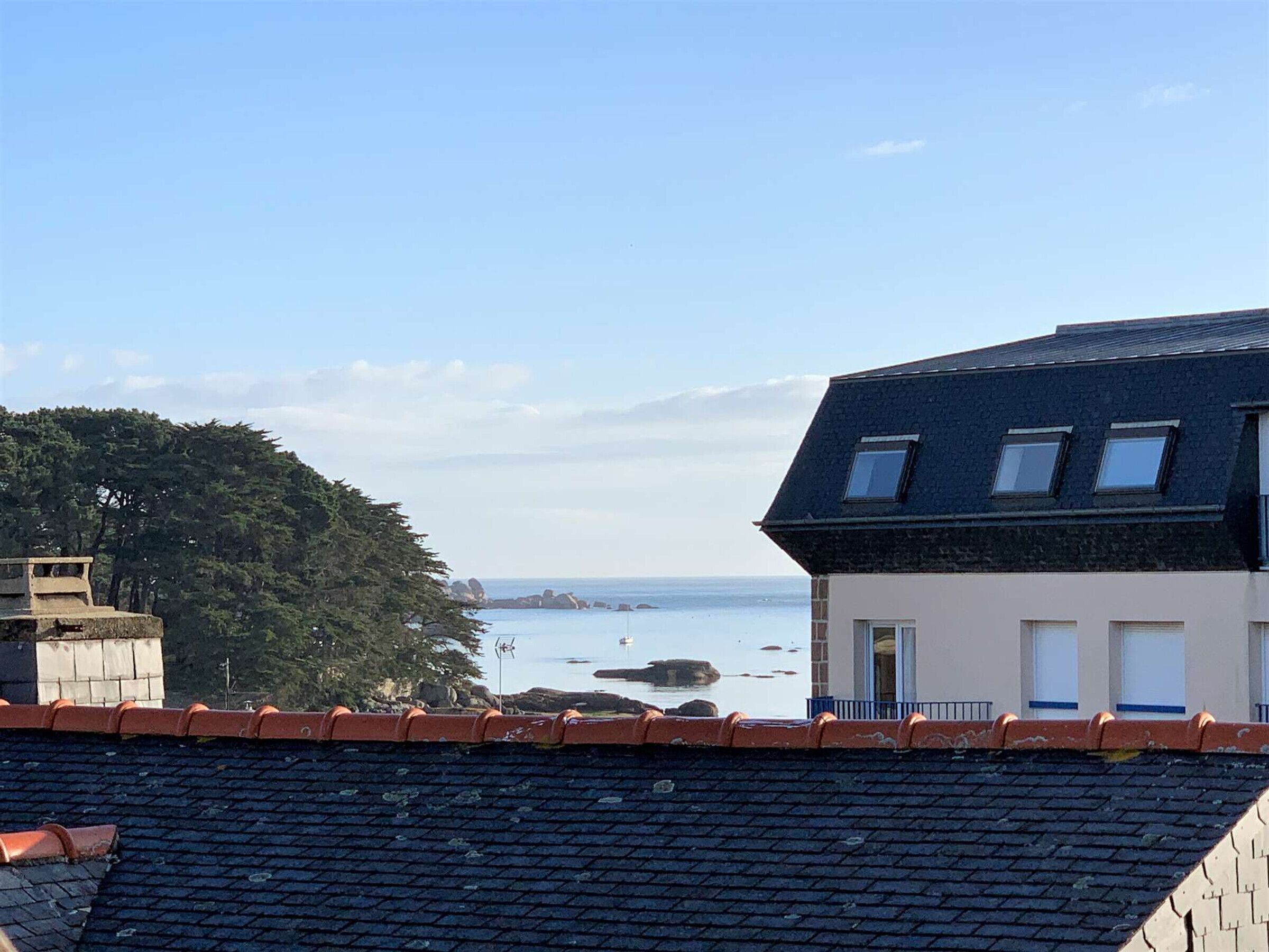 A coastal building with a sloped roof, a small balcony, and a view of the sea.