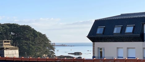 Un bâtiment situé sur la côte, doté d’un toit en pente, d’un petit balcon et offrant une vue sur la mer.