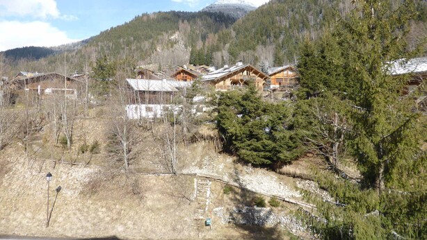 Un rifugio alpino con case di legno, immerso tra alberi e un cielo sereno.