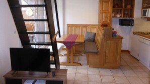 Una cucina compatta con mobili in legno, un forno a microonde e un piccolo angolo ristoro con una panca e un tavolo.
