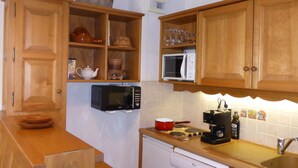 Una cucina compatta con mobili in legno, un forno a microonde, una macchina da caffè e un’lavastoviglie.