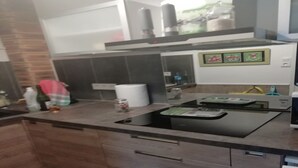 Une cuisine moderne avec un plan de travail noir, des armoires en bois et un évier en acier inoxydable.