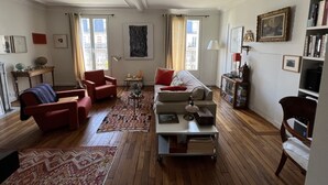Un salon spacieux comprenant un canapé, des fauteuils, une table basse et une bibliothèque.