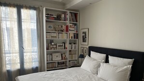 Une chambre à coucher avec un grand lit, une bibliothèque et une fenêtre avec des rideaux.