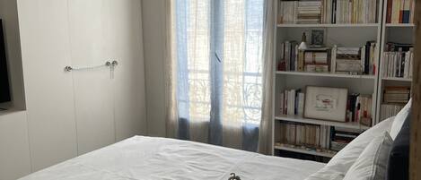 Un dormitorio con cama, lámpara de noche, estantería y armario.