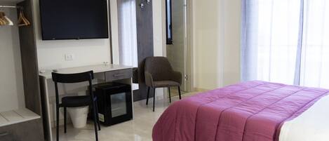 Un dormitorio con cama, escritorio, silla y televisión.