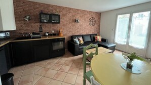 A compact living space with a kitchen, a dining area, and a seating area with a sofa and chairs. - Charming, quiet duplex cottage with terrace/garden (Ardon)