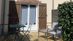 A house with a wooden deck, two doors, and a small patio area with chairs and a table. - Charming, quiet duplex cottage with terrace/garden (Ardon)