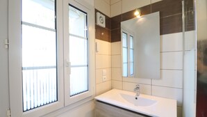 Een badkamer met een groot raam, een wastafel en een spiegel.