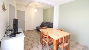 Een eetgedeelte met een houten tafel en stoelen, een computer op een bureau en een bank tegen de muur.