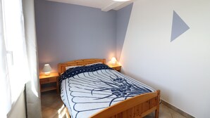 Een slaapkamer met een houten bed, twee bedlampen en een lichtgekleurde muur.