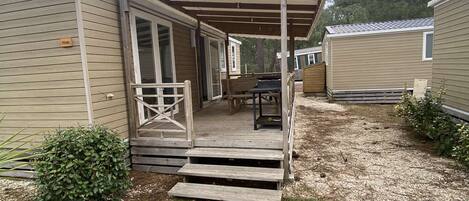 A mobile home with a covered porch and a small deck.