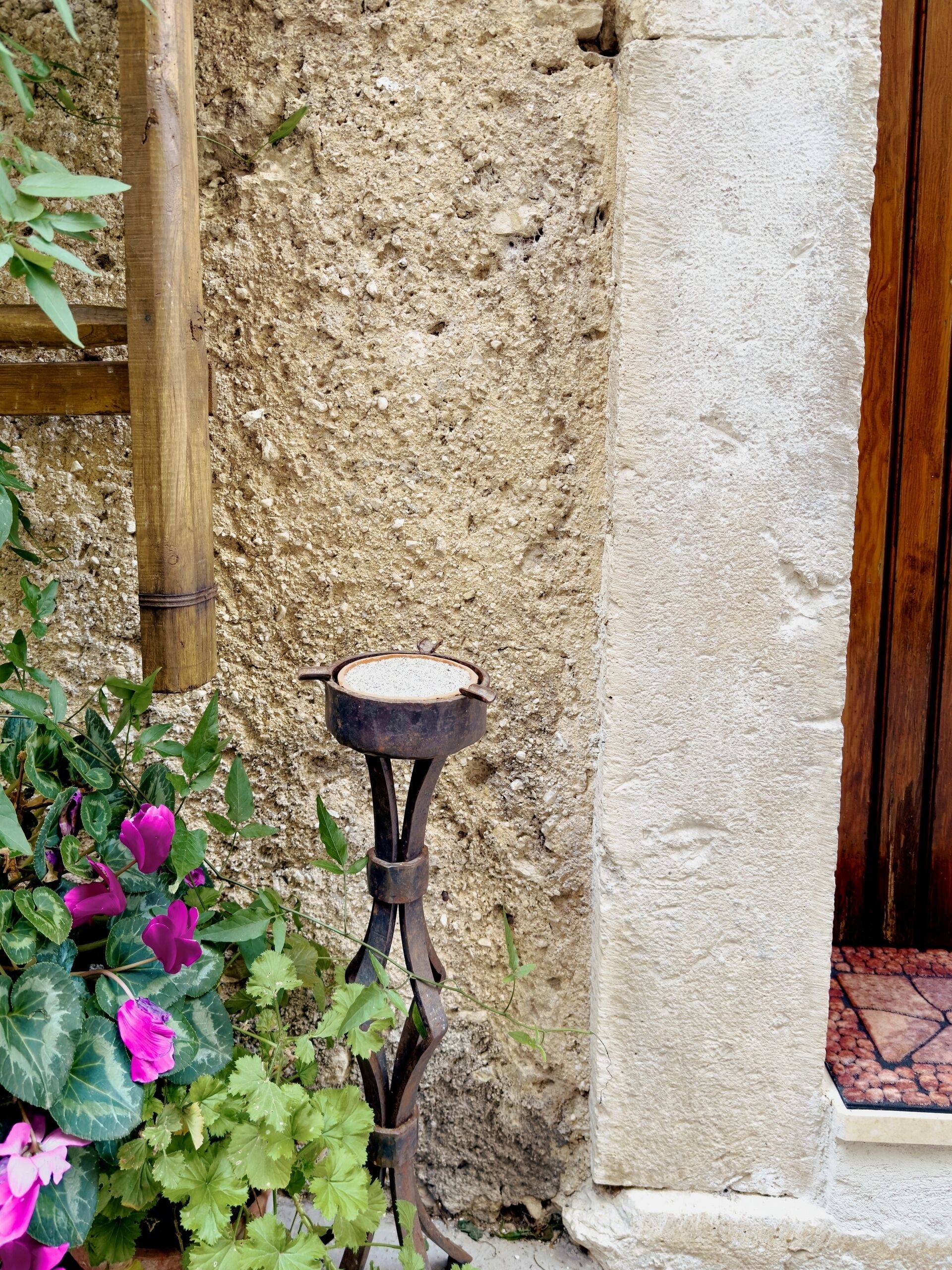Un entorno rústico al aire libre con una mesa metálica y una escalera de madera apoyada en una pared con textura.