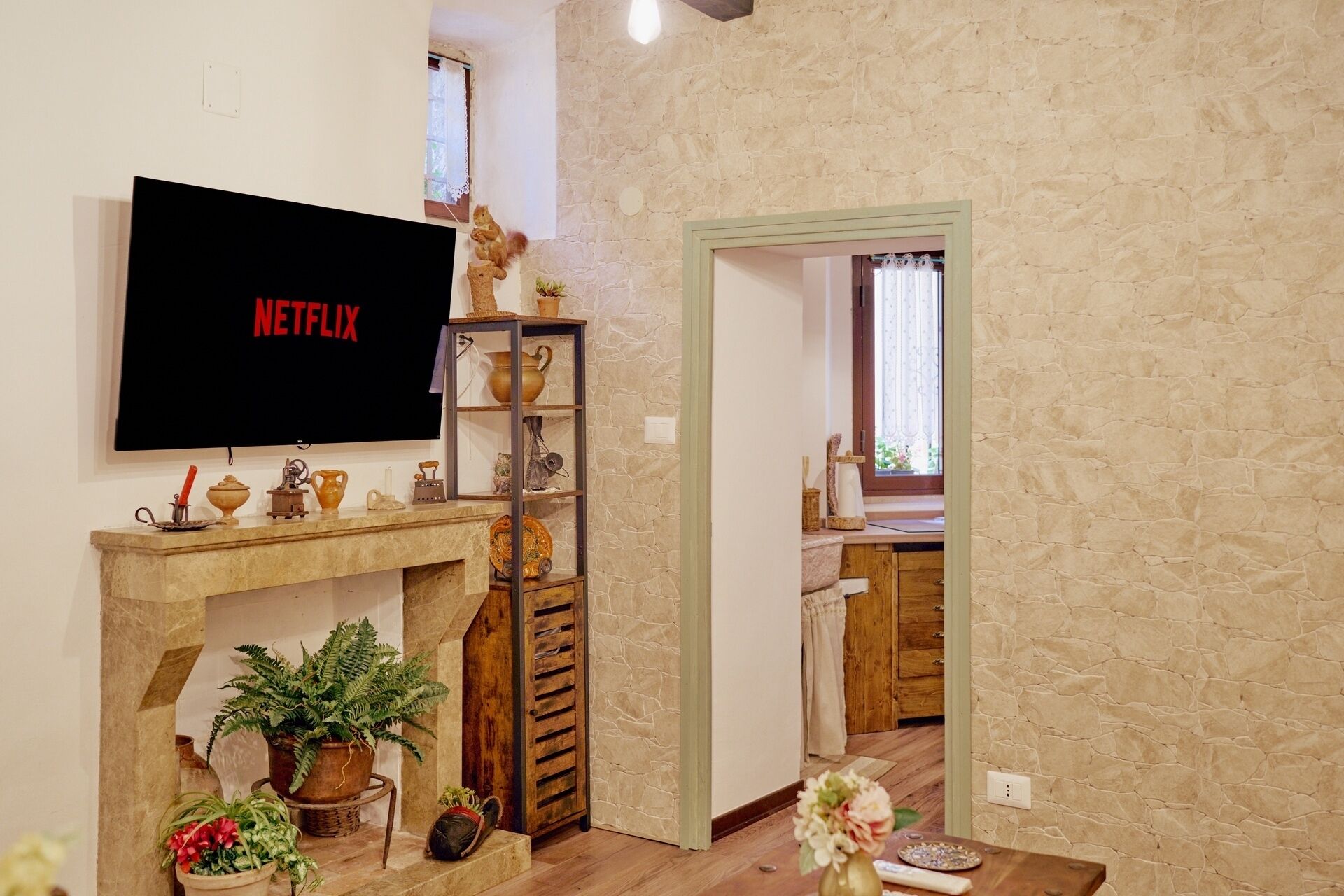 Una sala de estar con una pared de piedra, una chimenea y un televisor que muestra 'NETFLIX'.