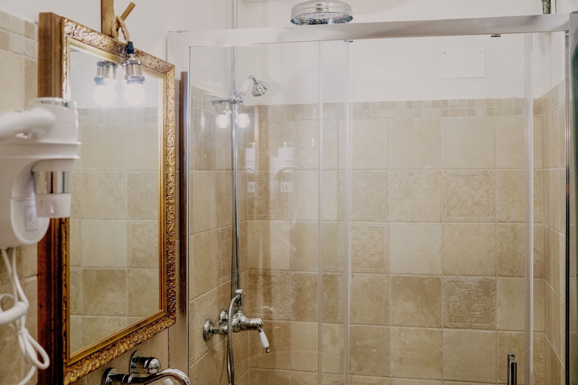 Ein Badezimmer mit Duschkabine aus Glas, einem großen Spiegel und einem Handtuchhalter.
