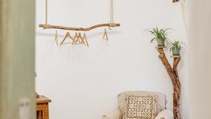 Ein Schlafzimmer mit einem Bett, einem Holzbstuhl, einem kleinen Tisch, einer Chandelier und einer Pflanze.