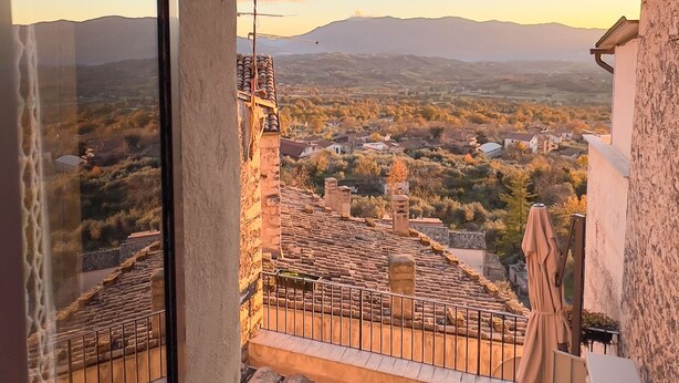 Ein Balkon mit Blick auf eine Stadt und Berge bei Sonnenuntergang.