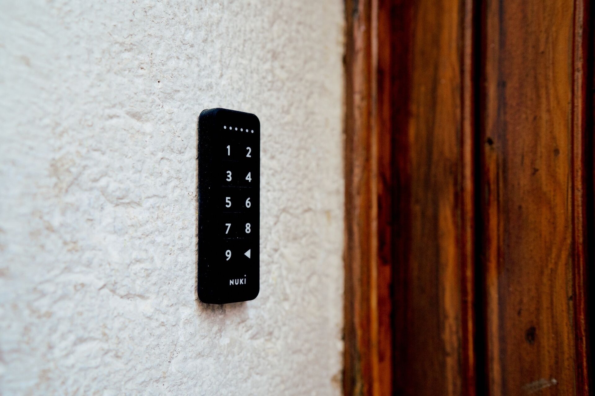 A black numeric keypad mounted on a textured wall, likely for a door lock.