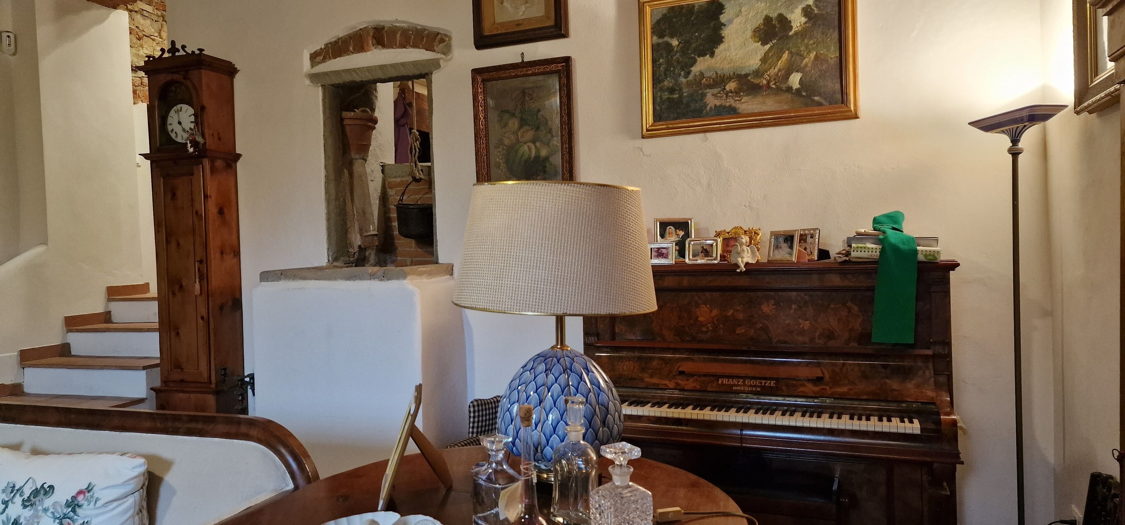 Ein Wohnzimmer mit einem Klavier, einer Uhr, einer Lampe und einer Treppe.