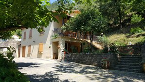 Un edificio con un balcone, gradini in pietra e piante in vaso.
