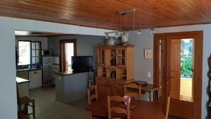 Una cucina compatta con mobili in legno, un tavolo da pranzo con sedie e un televisore.