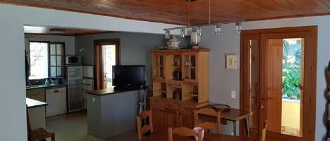 Una cocina compacta con armarios de madera, una mesa de comedor con sillas y un televisor.