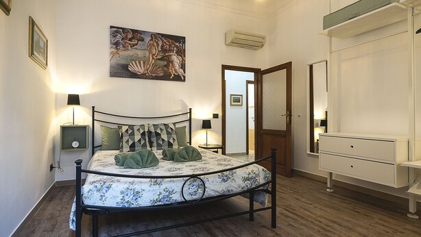 Ein Schlafzimmer mit einem Bett, Nachttischlampen, einem Schminktisch und einem Bild an der Wand.