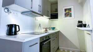 A compact kitchen with white cabinets, a black coffee maker, a microwave, and a small oven. - Magnificent view, hyper center apartment (Tours)