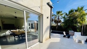 A modern house with a dining area, a patio with chairs, and a pool. - 180 M2 architect-designed villa near Montpellier and beaches (Lattes)