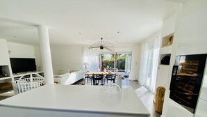 A modern kitchen with a central island, dining area, and a large window providing natural light. - 180 M2 architect-designed villa near Montpellier and beaches (Lattes)