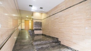 Uma escadaria de mármore com corrimãos, conduzindo a uma porta no topo.