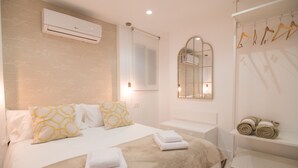 Quarto de hotel com cama, espelho, ar condicionado e porta-toalhas.