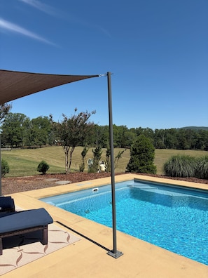 A swimming pool with a pergola and lounge chairs.