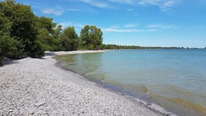 A pebbled beach with clear water and trees in the background. - Jackson's Falls Country Inn (Prince Edward)