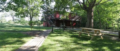 A picnic table and a brick pathway in a park with trees and a building in the background.