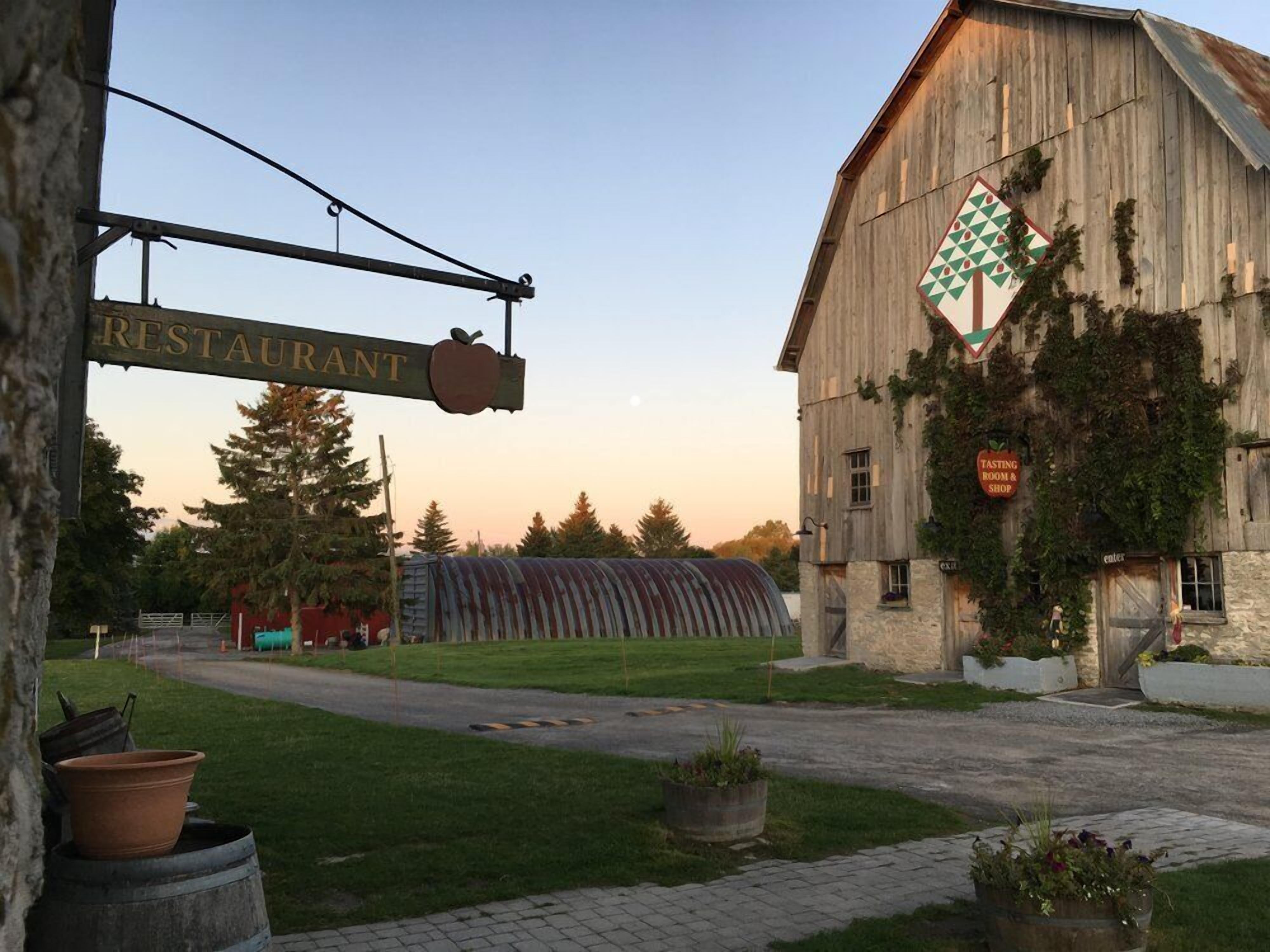 A rustic barn with a sign for a restaurant and a tasting room & shop.